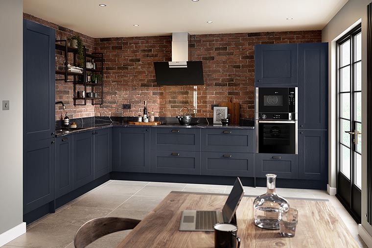Shaker wood kitchen in indigo blue with limestone floor and red brick feature wall.