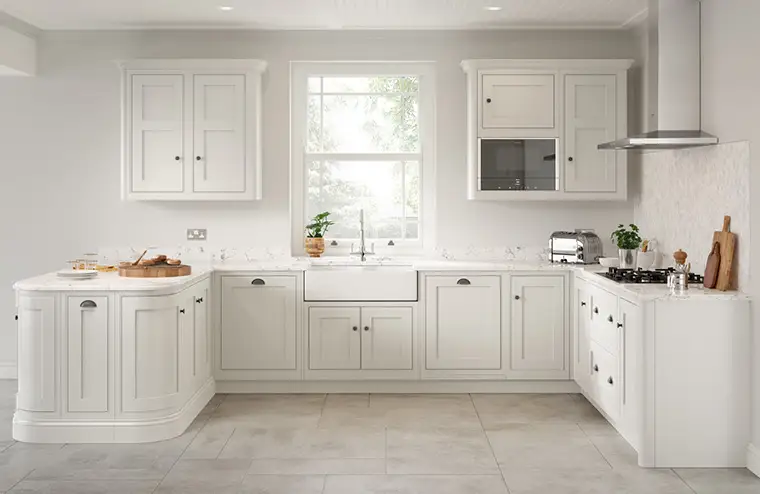 White inframe kitchen with white quartz worktop and light stone flooring.